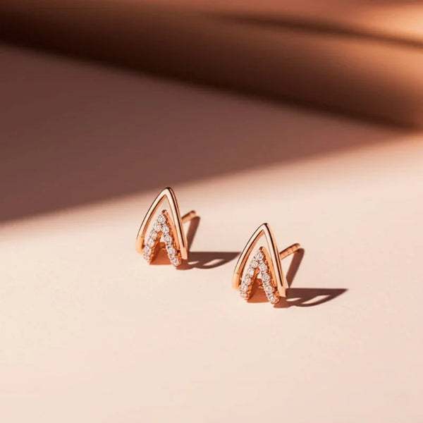 Rose gold earrings with diamond accents on a beige background