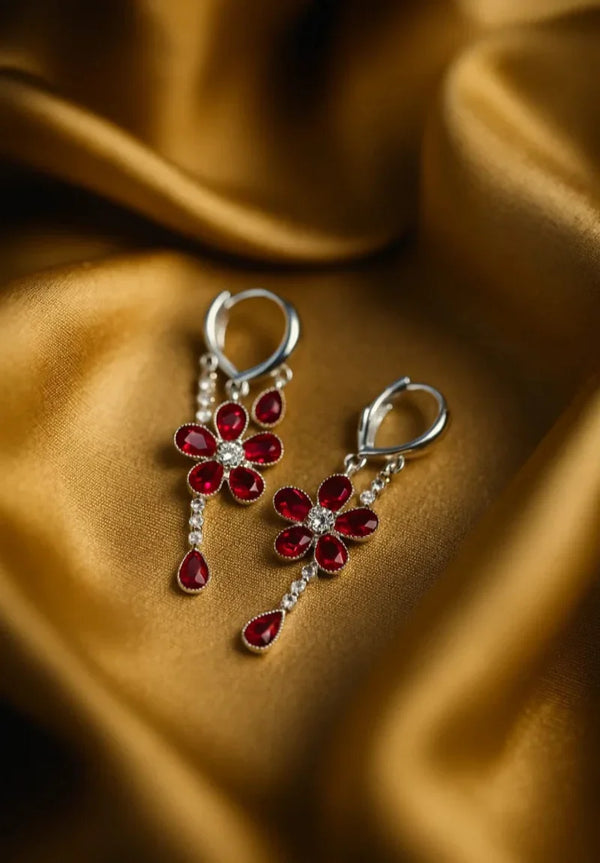 Floral earrings with red gemstones on a brown fabric background
