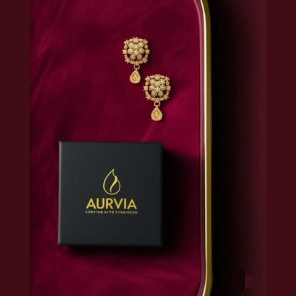 Gold earrings with a black Aurvia box on a red background