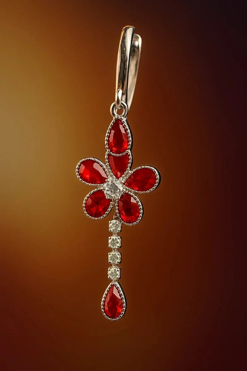 Jewelry pendant with red gemstones and a silver setting on a brown background