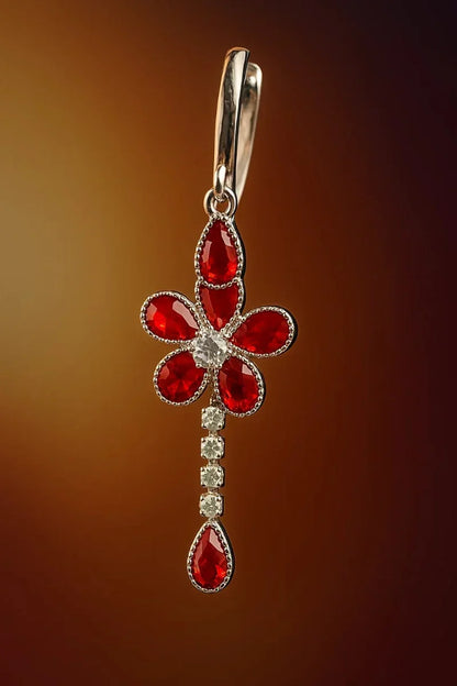 Jewelry pendant with red gemstones and a silver setting on a brown background